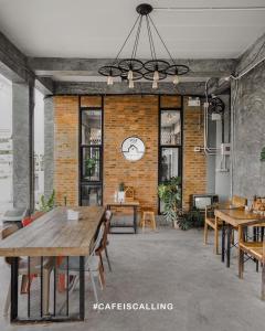 een kamer met tafels en stoelen en een klok aan de muur bij YOJI House and Cafe in Ban Wiang