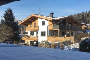 una casa en la nieve con una valla en Appartement Kollingwald, en Saalfelden am Steinernen Meer