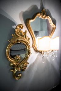 un espejo de oro colgando de una pared con una luz en Giò&Giò Venice B&B, en Venecia
