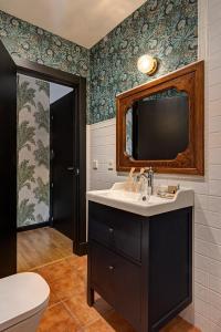 a bathroom with a sink and a tv on the wall at Hospedium Hotel La Farm in La Granja de San Ildefonso