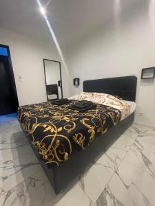 um quarto com uma cama com um cobertor preto e dourado em Suite cinéma et jacuzzi privé em Melun