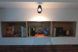 a shelf with books and a light on a wall at Volt76 - Como lake apartment in Como