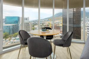 a table and chairs in a room with a large window at One Thibault Luxury Apartments in Cape Town