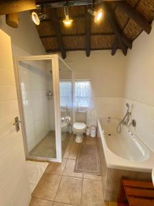 a bathroom with a bath tub and a toilet at Charihandra Game Lodge in Addo