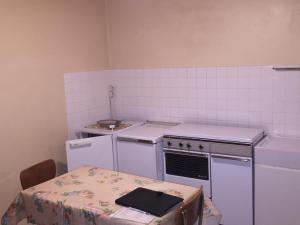 a small kitchen with white appliances and a table at Appartement Mont-Dore, 2 pièces, 2 personnes - FR-1-415-36 in Le Mont-Dore