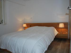 レ・サ​​ーブル・ドロンヌにあるAppartement Les Sables-d'Olonne, 3 pièces, 6 personnes - FR-1-197-356の白いベッド1台(木製ヘッドボード付)が備わるベッドルーム1室が備わります。