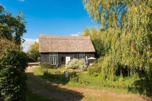 an old house in the middle of a field at Deepwell Granary is a lovely thatched barn with attached meadow woodland in Buxhall