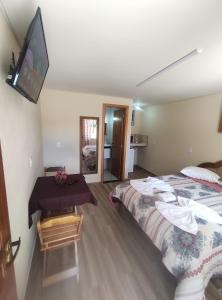 a bedroom with a bed and a table with a television at chales e aptos Carvalhos em monte verde in Monte Verde