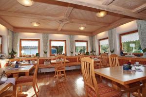 un restaurante con mesas y sillas de madera y ventanas en Landhaus Maltermoos, en Schönau am Königssee