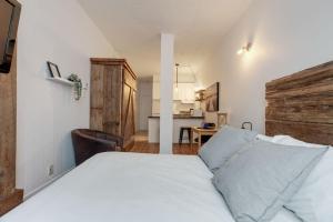 Un dormitorio con una cama blanca y una cocina. en Initial / La cabine / Québec, en Quebec