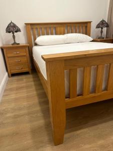 a bedroom with a wooden bed and two night stands at Premium flat! Enjoy luxurious white Egyptian bedding near Gants Hill Station, Ilford, London in Wanstead