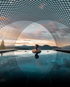 un hombre sentado en una piscina de agua en una piscina en Gloriette Guesthouse Hotel & Restaurant, en Soprabolzano