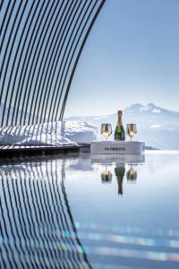 two wine bottles sitting on a table next to a body of water at Gloriette Guesthouse Boutiquehotel in Soprabolzano