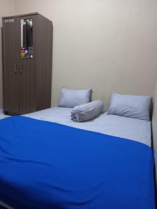 - une chambre avec 2 lits avec des draps bleus et une armoire dans l'établissement EKSOTIS ROOMS SYARIAH, à Seturan