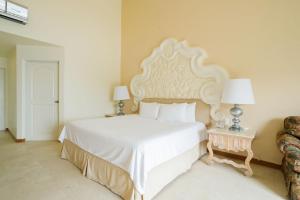 a bedroom with a large white bed and a chair at Quinta Real Acapulco in Acapulco