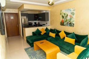 uma sala de estar com um sofá verde e almofadas amarelas em PUERTO MARINA ASILAH em Asilah