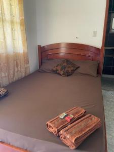 a bed with a wooden headboard and two towels on it at Pousada Boa Vista in Cachoeiras de Macacu