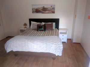 una camera da letto con un grande letto con lenzuola e cuscini bianchi di Fisherhaven Guest House a Hermanus