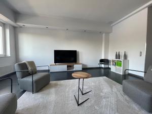 a living room with a tv and a couch and a table at TruRetreats Design Loft I Riesige Küche I Wallbox I 65z SmartTV I 150qm in Hamburg