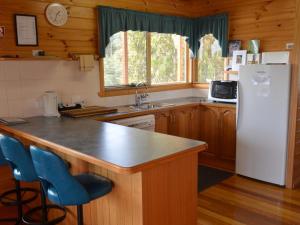 a kitchen with a white refrigerator and a sink at Coles Bay House in Coles Bay