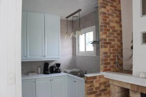 a kitchen with white cabinets and a brick wall at GITE AVEC SPA ENTRE FORET ET PLAGE - Ambiance Bord de Mer in Saint-Hilaire-de-Riez +10 photos