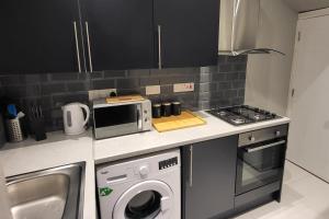a kitchen with a washing machine and a microwave at Park House Modernised 2 Bedroom Property in Knowsthorpe