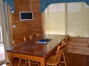 a dining room table with chairs and a television at Coles Bay House in Coles Bay