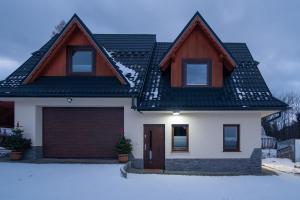 ein weißes Haus mit einem braunen Dach und einer Garage in der Unterkunft Oczko Na Giewont in Kościelisko