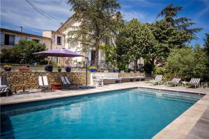 a swimming pool with chairs and a table and an umbrella at Cottage provencal - Villa saint Marc in Forcalquier