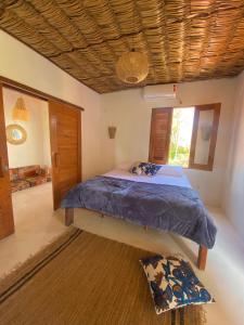 a bedroom with a bed with a blue comforter and a window at Casa Nature Atins in Atins