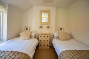 a bedroom with two beds and a mirror on the wall at CROYDE VICTORIA COTTAGE 2 Bedrooms in Croyde