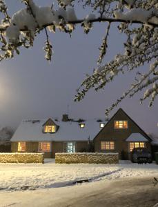 une maison éclairée dans la neige dans l'établissement Cornerways B&B, à Chipping Campden