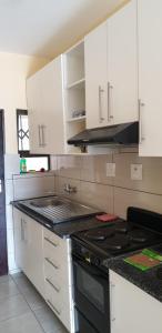 cocina con armarios blancos y fogones en Manzini, Park Vills Apartment, No 103, en Manzini