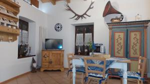 ein Esszimmer mit einem Tisch und einem TV in der Unterkunft Loft della Perpetua di Casa Bernardi, romantica mansarda nelle Dolomiti di Brenta in Montagnaga