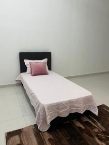 Una cama con una almohada rosa encima. en Homestay Kemaman Fyna04 dekat Pantai Geliga en Kampong Kemaman