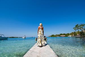 a woman standing on a dock in the water at Isla Tijereto in Isla Grande