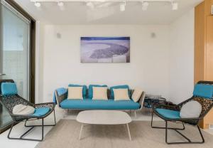 ein Wartezimmer mit einem blauen Sofa und zwei Stühlen in der Unterkunft Spacious 5BR Penthouse Sea views by Holyguest in Tel Aviv
