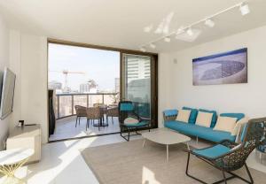 ein Wohnzimmer mit einem blauen Sofa und Stühlen in der Unterkunft Spacious 5BR Penthouse Sea views by Holyguest in Tel Aviv