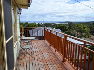 un balcón de madera con mesa y sillas. en Coles Bay House en Coles Bay