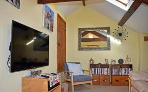 a living room with a flat screen tv and a chair at The Snickett in Combe Martin