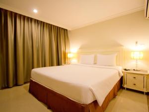 芭達雅中心的住宿－LK大廈公寓式酒店，卧室设有一张白色大床和一扇窗户。