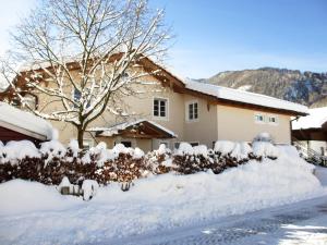 una casa cubierta de nieve con un patio en Ferienwohnung Schrödel en Aschau im Chiemgau