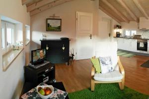 a living room with a television and a white chair at Ferienwohnung Schrödel in Aschau im Chiemgau