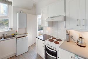 cocina con armarios blancos y fogones en ILFRACOMBE EDEN 2 Bedrooms, en Ilfracombe