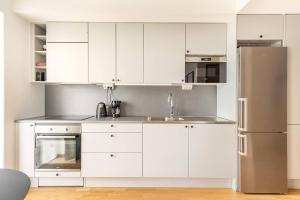 kuchnia z białymi szafkami i lodówką ze stali nierdzewnej w obiekcie Luxury Business Studio Apartment - Garden View w mieście Sundbyberg