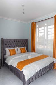 ein Schlafzimmer mit einem großen Bett mit einem orangenen Vorhang in der Unterkunft Springstone executive apartment Rm 15 in Langata Rongai