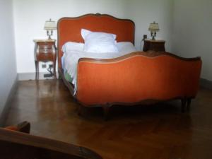 ein orangefarbenes Bett mit weißer Bettwäsche und Kissen in einem Zimmer in der Unterkunft Maison Barbarenekoborda in Villefranque