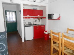 eine kleine Küche mit roten Schränken und einem Tisch in der Unterkunft Maison Ploemel, 2 pièces, 4 personnes - FR-1-397-13 in Ploemel
