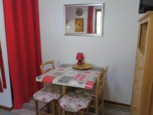 mesa de comedor con sillas y lámpara roja. en Studio Châtel, 1 pièce, 4 personnes - FR-1-198-128, en Châtel