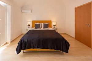 una camera da letto con un letto con una coperta nera sopra di Luxury Palm Suites a Reguengos de Monsaraz